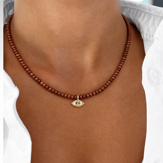 Model wearing a delicate goldstone beaded necklace with a clear marquise-shaped CZ pendant and 14K gold-filled details.