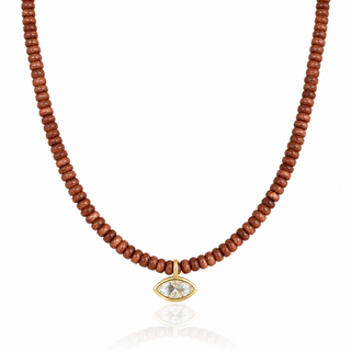 Close-up of clear marquise-shaped cubic zirconia pendant in a gold setting with shimmering brown goldstone beads.