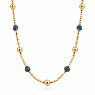 Close-up of blue cubic zirconia pavé balls and polished gold beads on a delicate 14K gold-filled necklace.