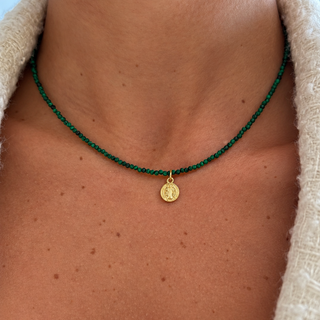 Model wearing a delicate green malachite beaded necklace with a small Saint Benedict medal pendant in 14K gold filled.