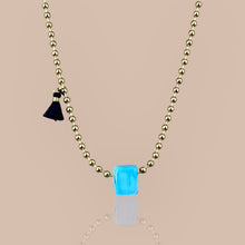 Load image into Gallery viewer, Close-up of a gold beaded chain necklace with a turquoise cube pendant, symbolizing luck and elegance
