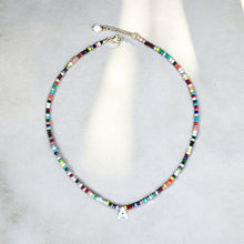 Load image into Gallery viewer, Detailed view of Mother of Pearl initial pendant and multicolor beaded necklace.
