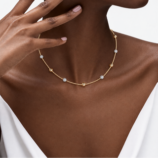 Model wearing a 14K gold-filled beaded necklace with clear cubic zirconia ball accents and polished gold spheres.