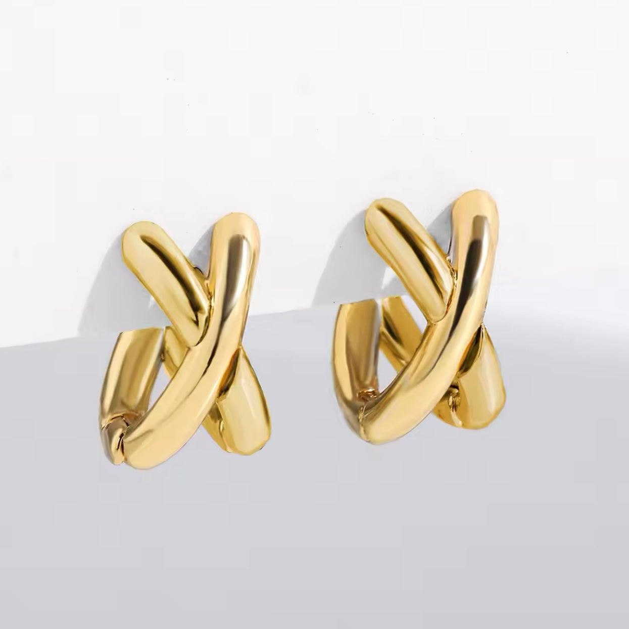 Close-up of Criss Cross Earrings in gold stainless steel, showcasing their sleek and modern design